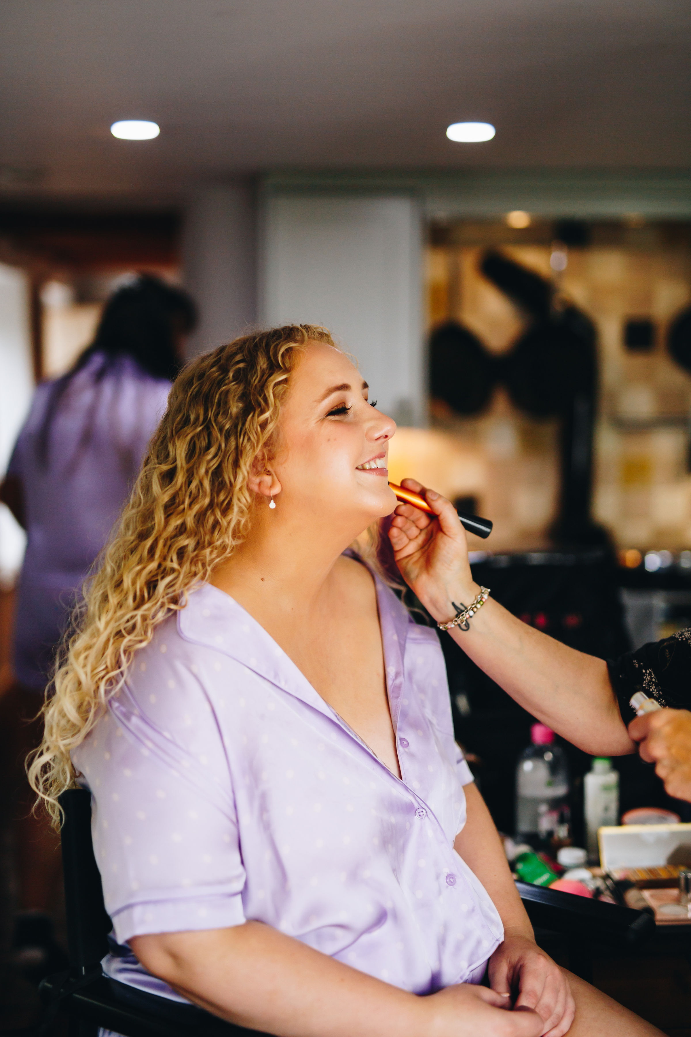 Bride smiling while getting her make up done