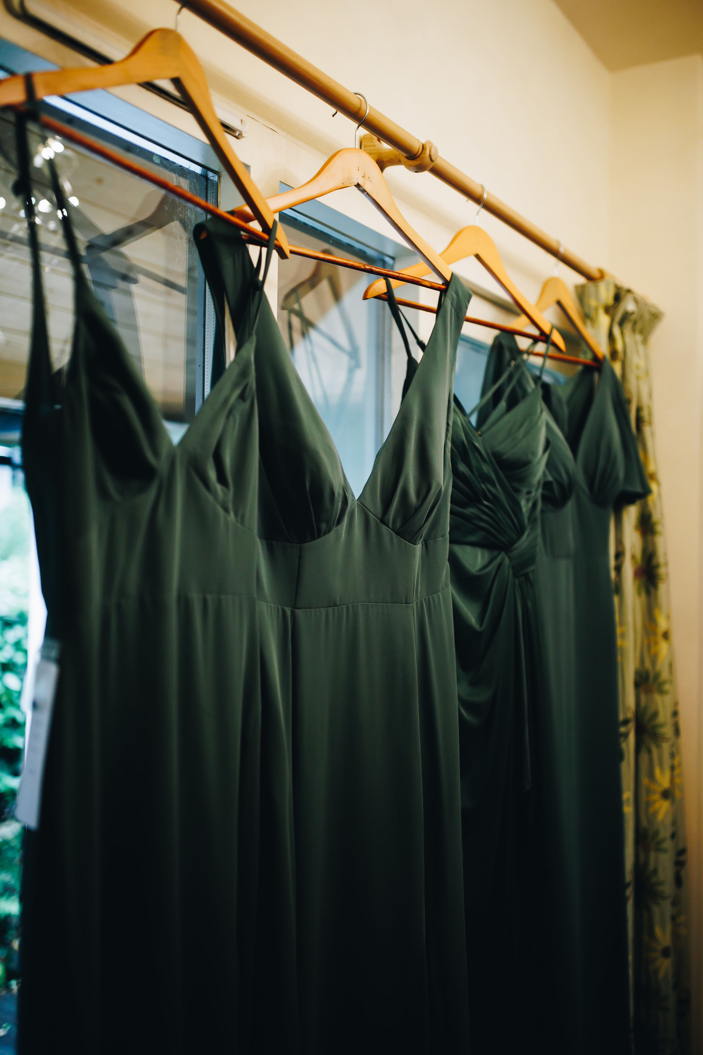 Teal bridesmaid dresses hanging on curtain pole
