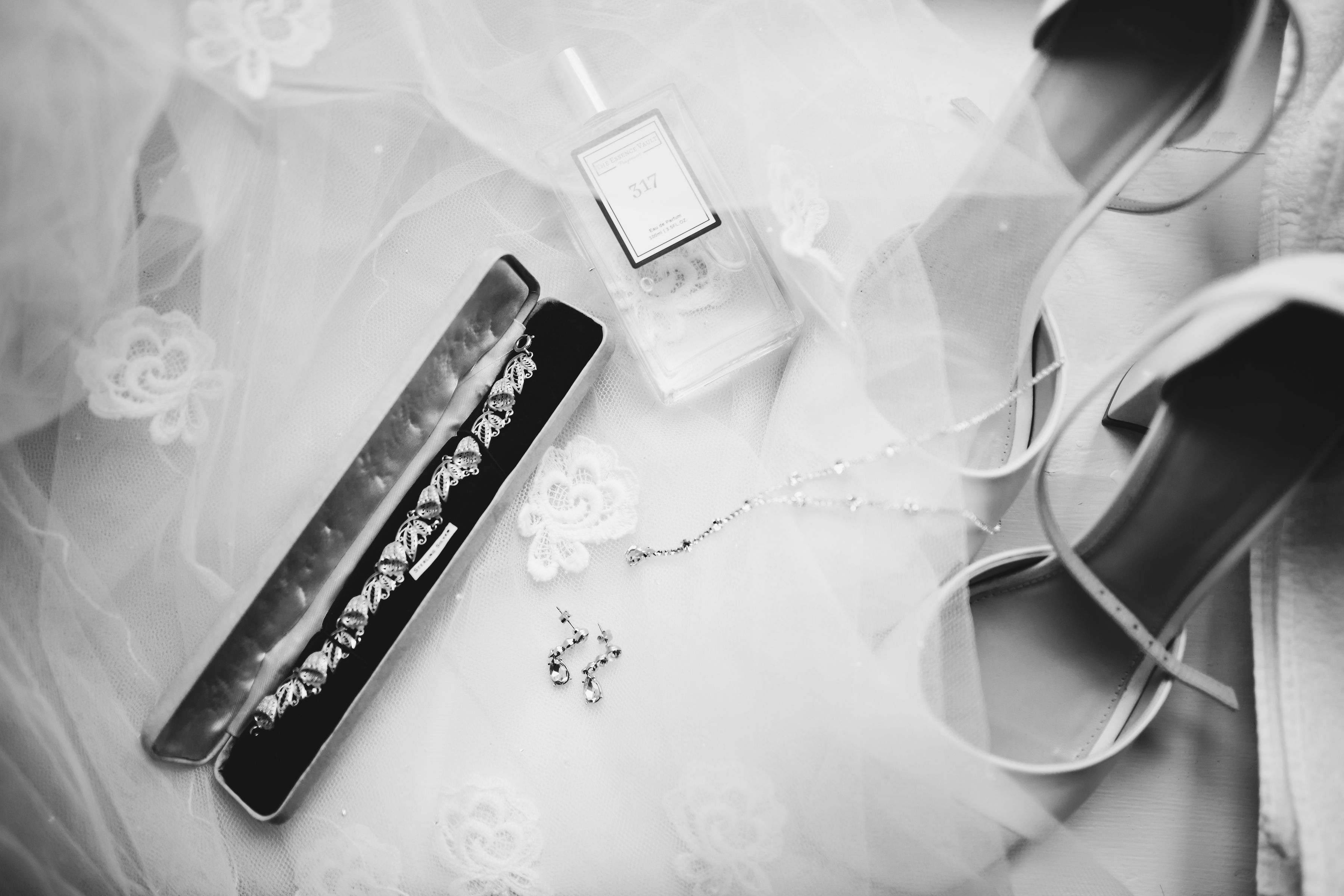 Flatlay of bridal shoes, jewellery, perfume and veil