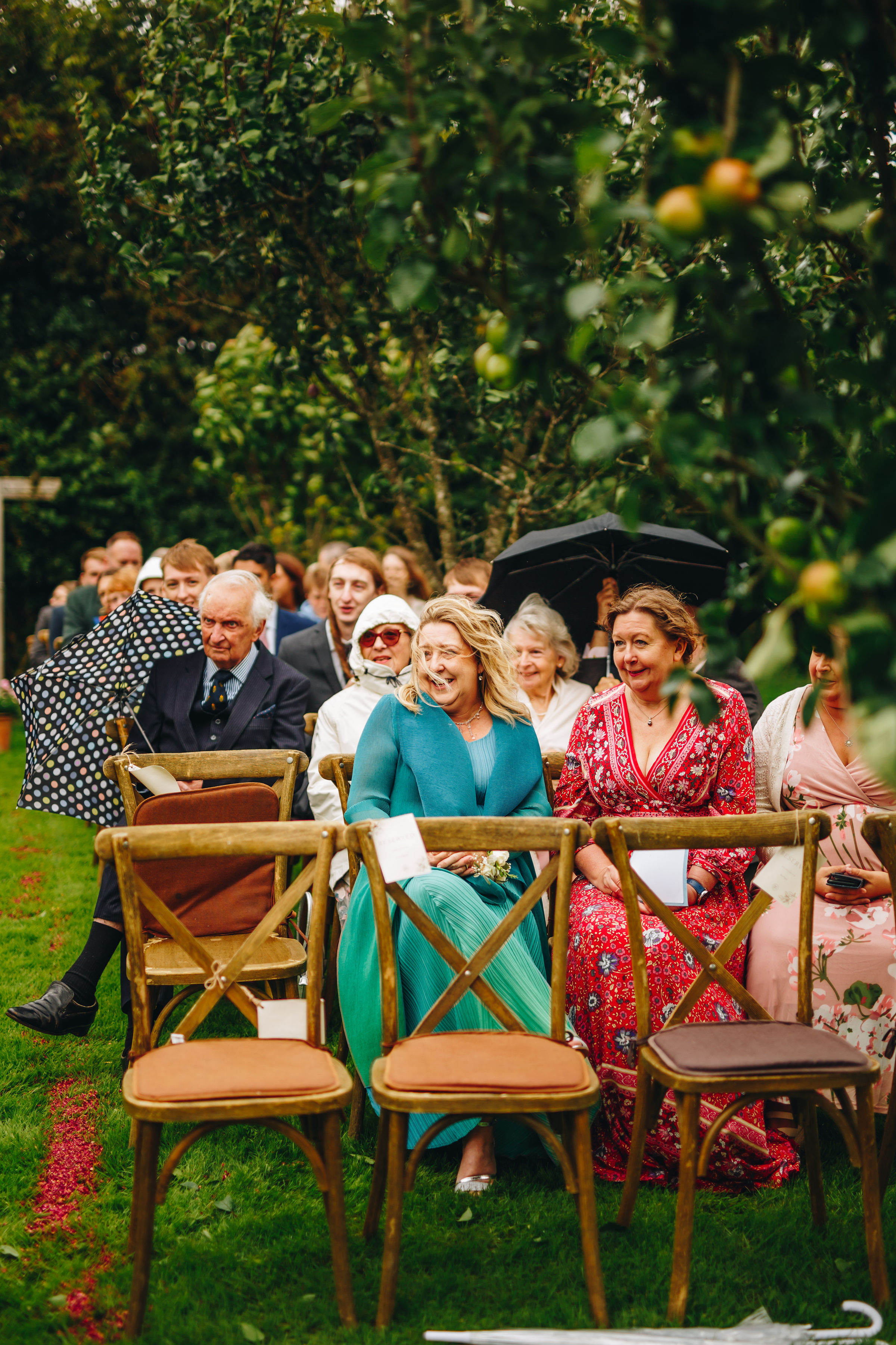 Wedding guests sit in the breeze and drizzle in excitement before a wedding starts