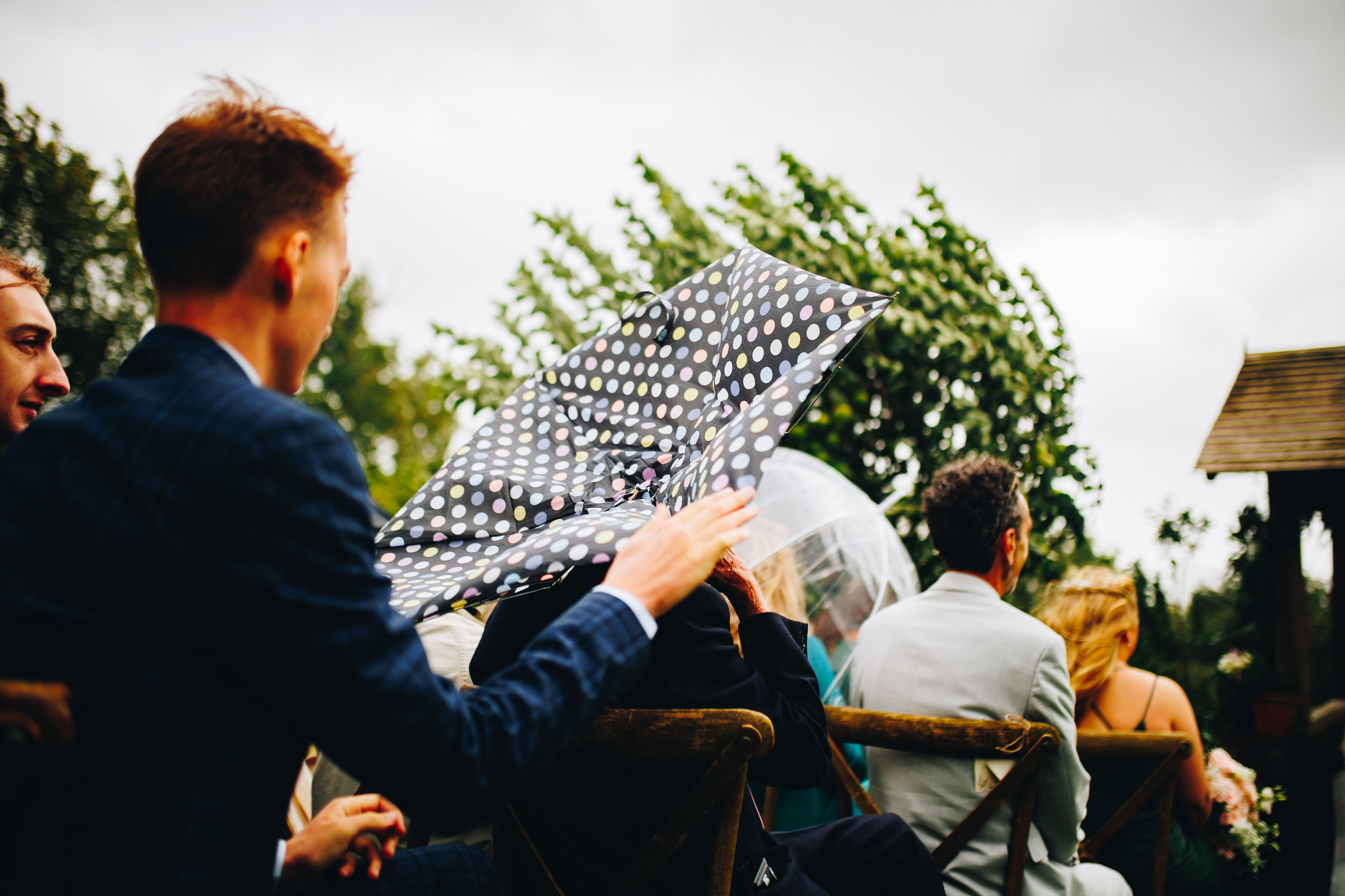 A spotty umbrella goes inside out, with people seated everywhere