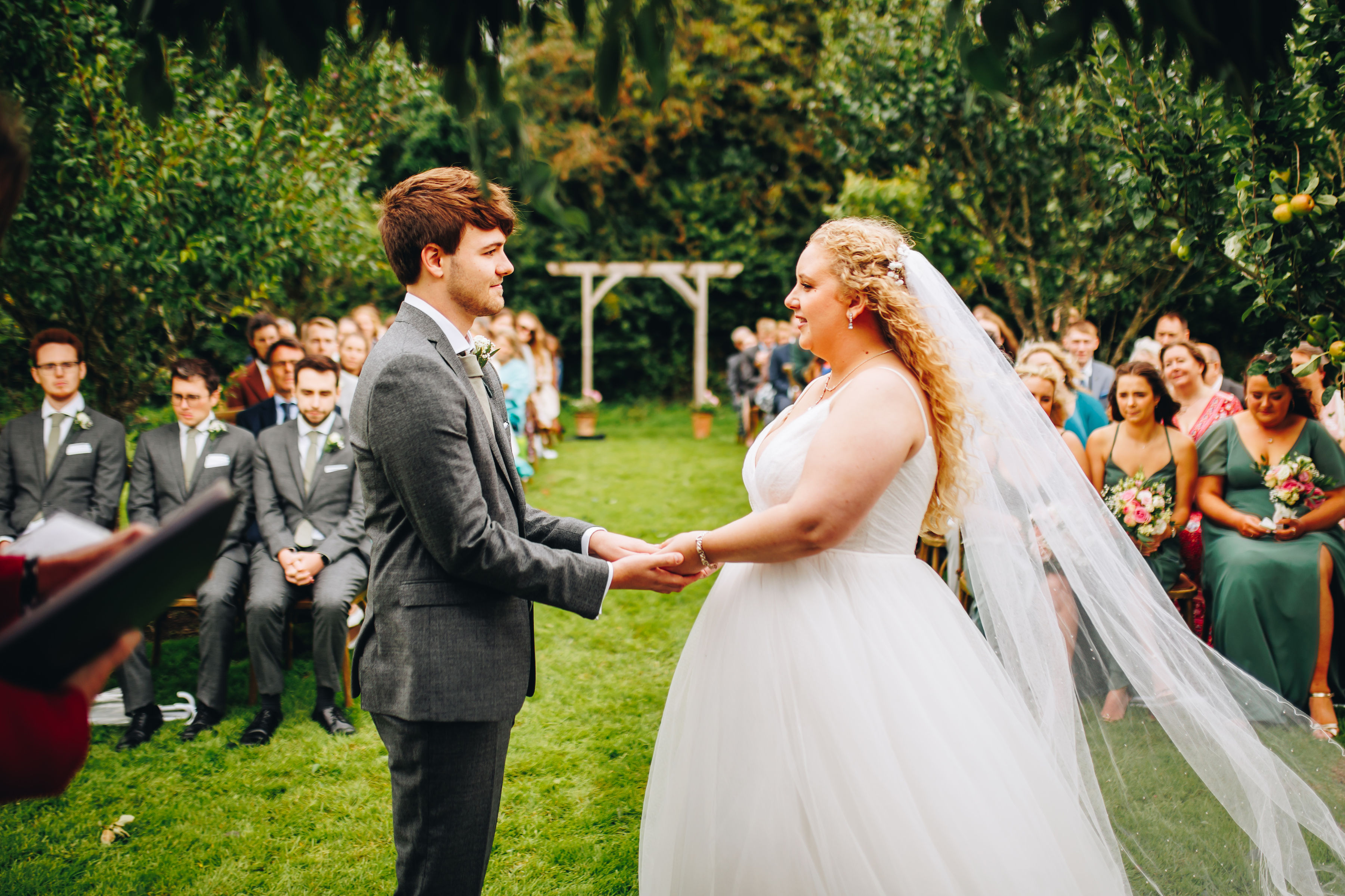 Bride and groom holding hands at their wedding ceremony in the breeze
