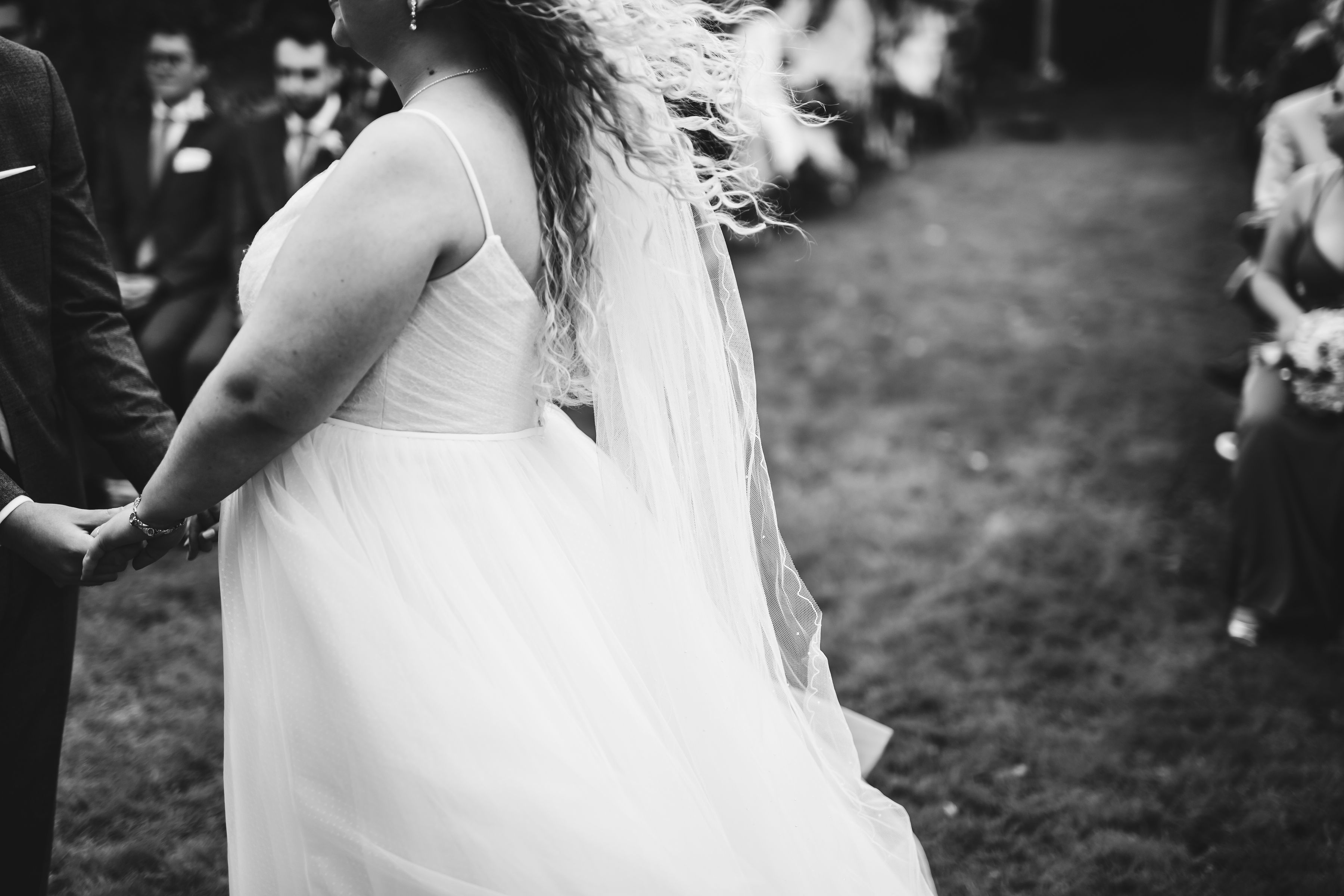 Black and white photo of bride's curly hair and veil moving in the breeze