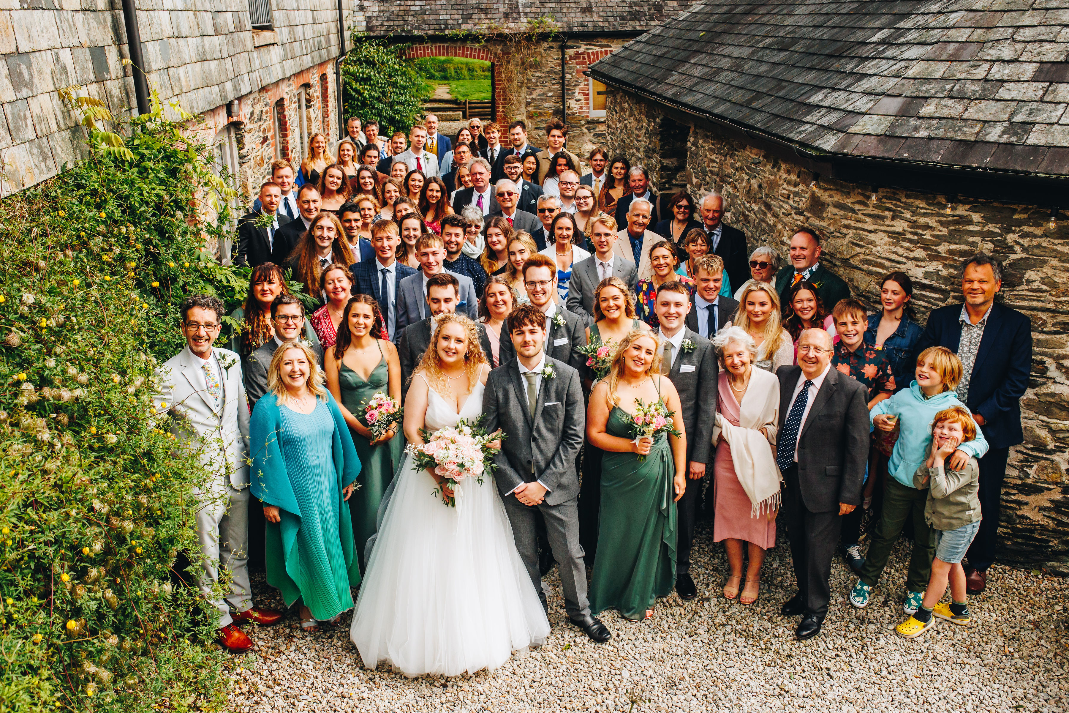 Group photo of wedding party from above in a rustic courtyard