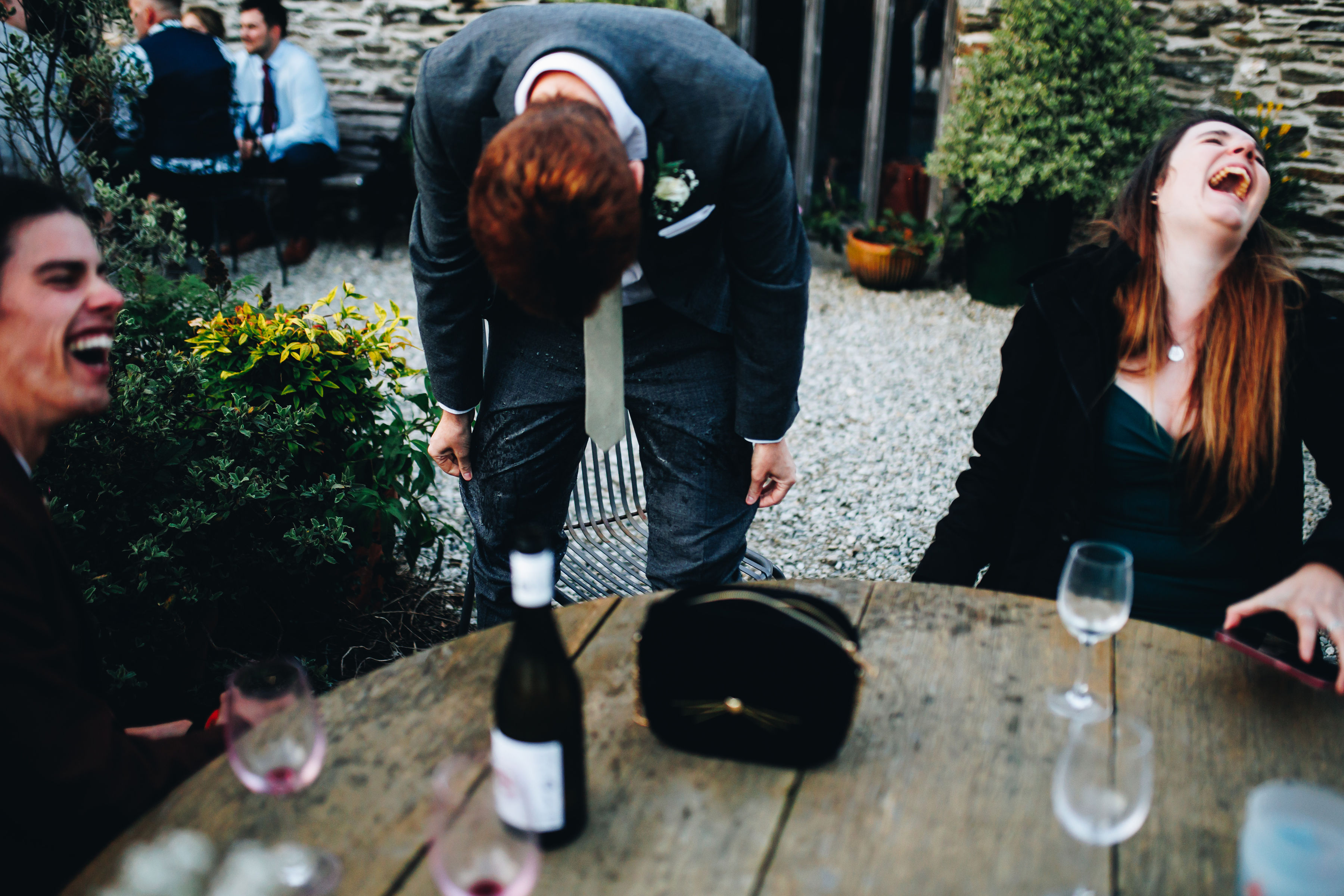 Guest stood up with drink spilt on him with other guests laughing