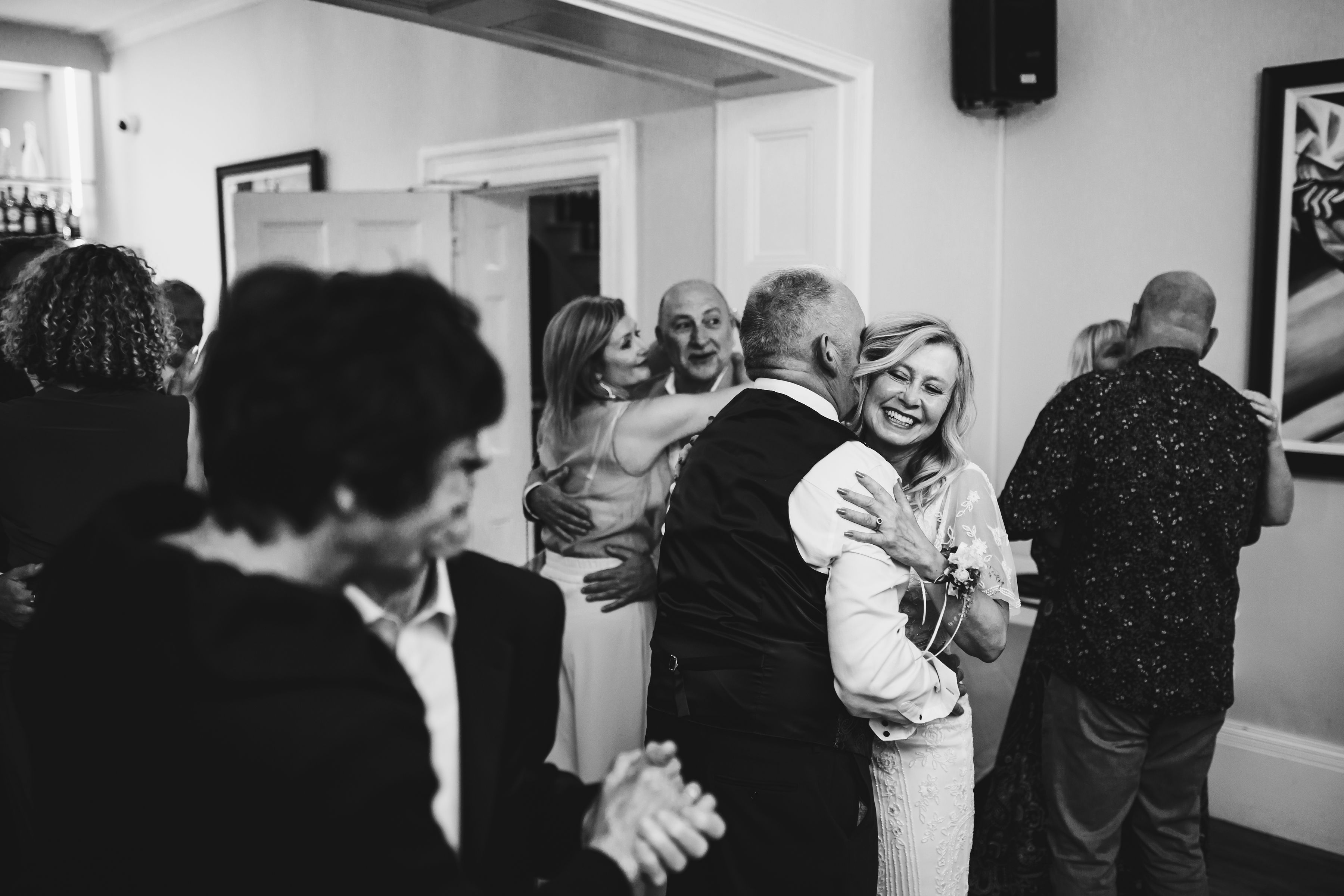 Black and white photo of couple dancing amongst guests