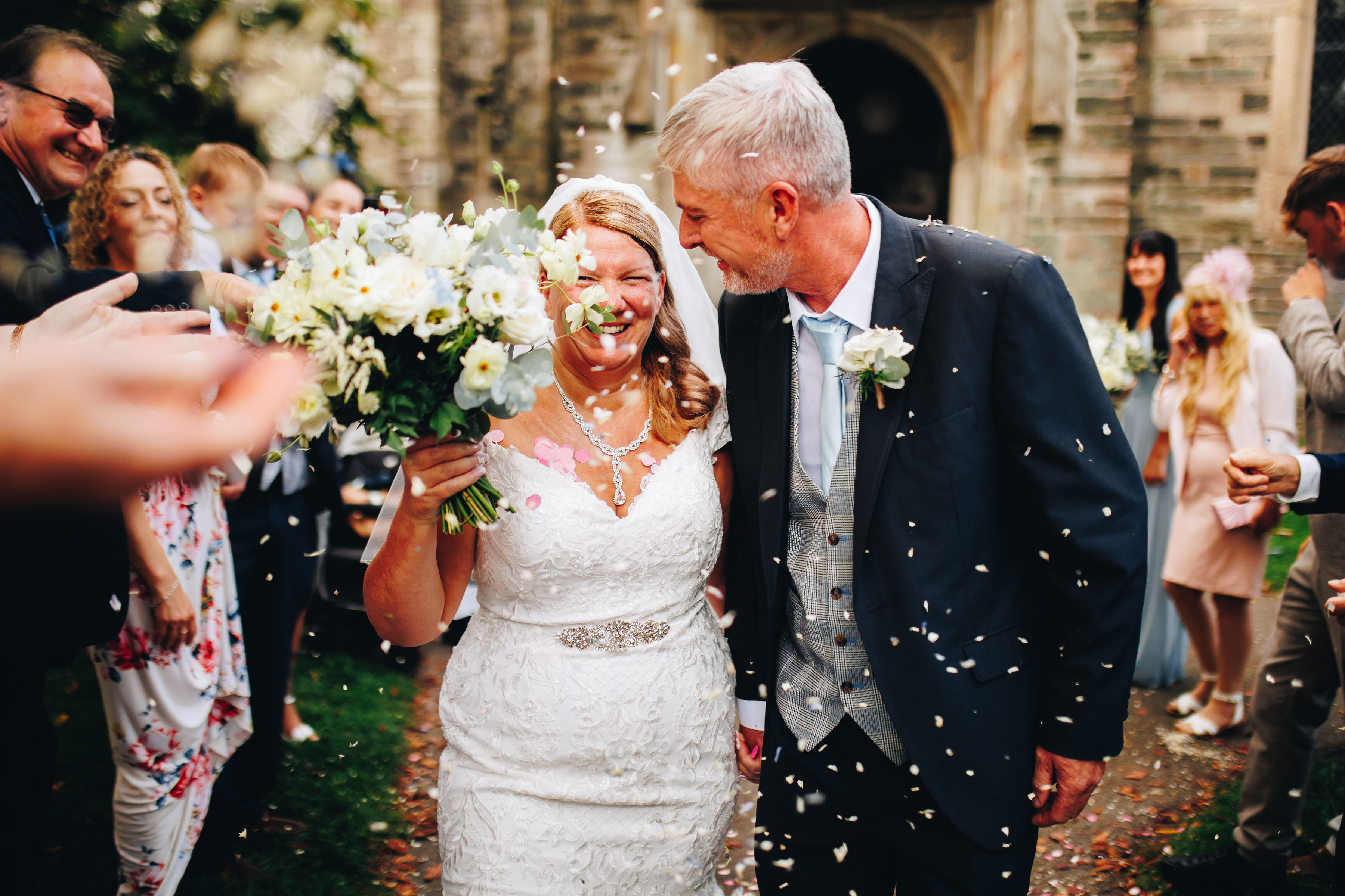 Bride and groom walk through confetti smiling