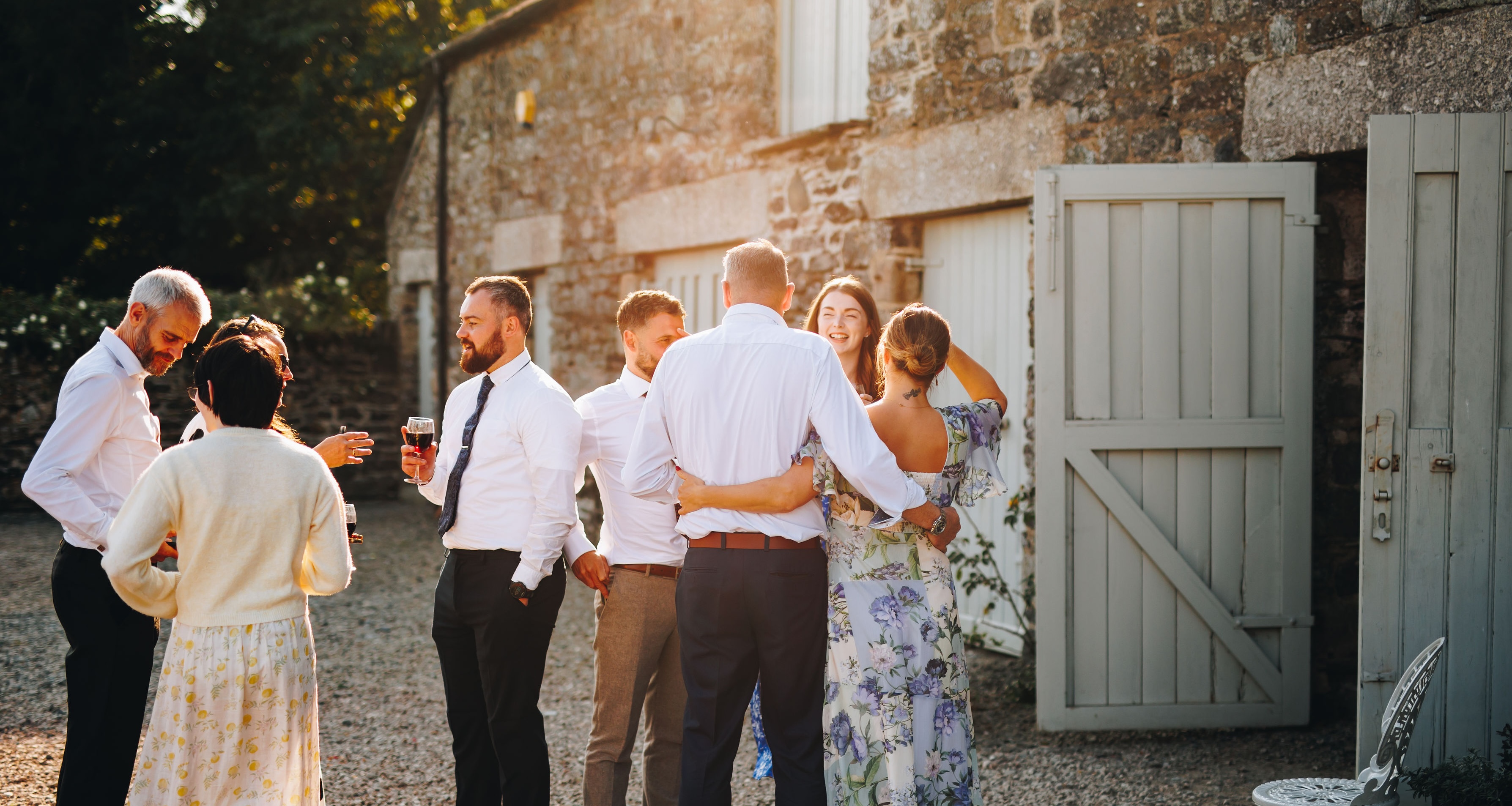Wedding guests mingling and laughing in the evening sunlight