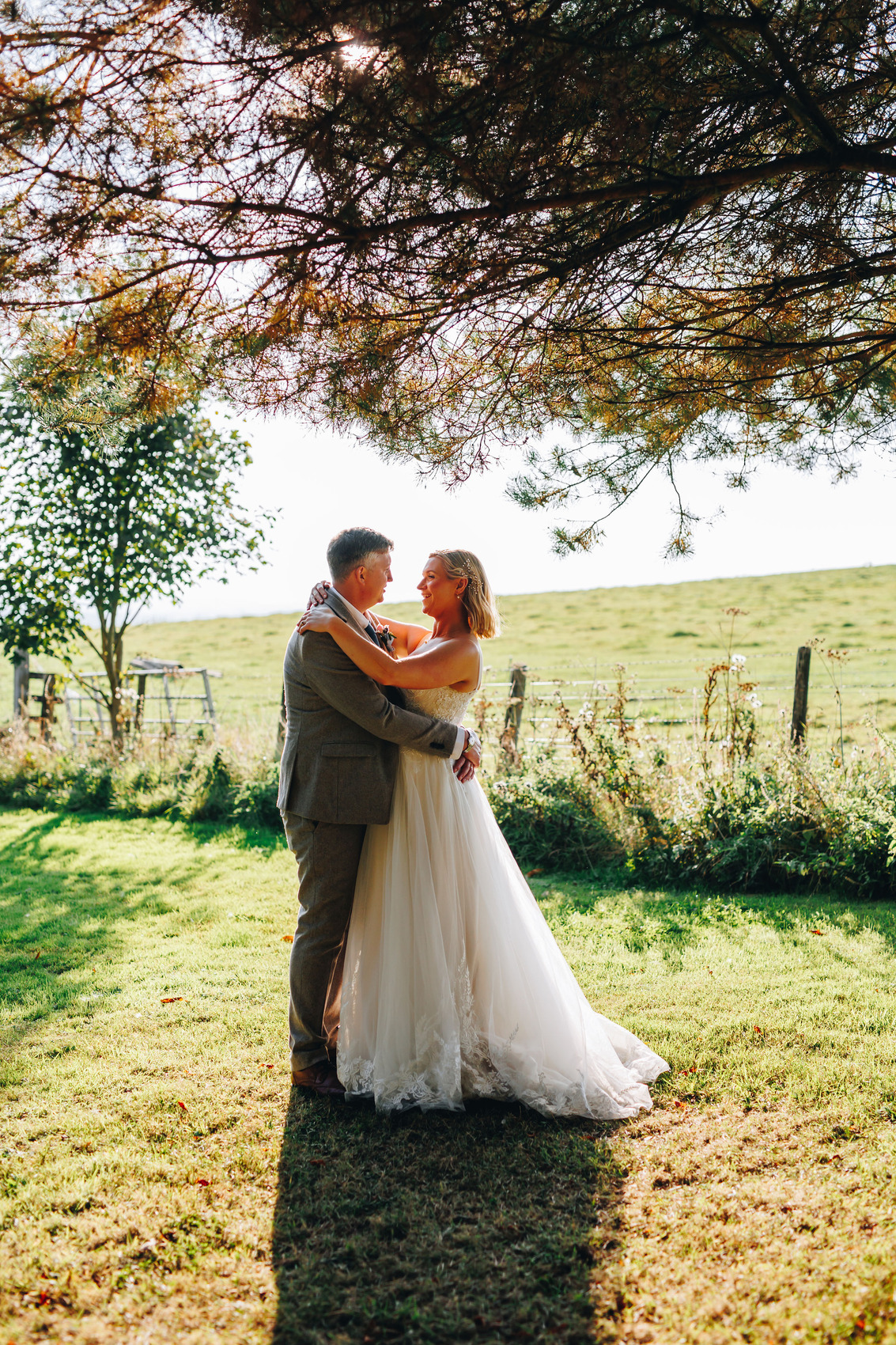 Bride and groom snuggled up under the trees