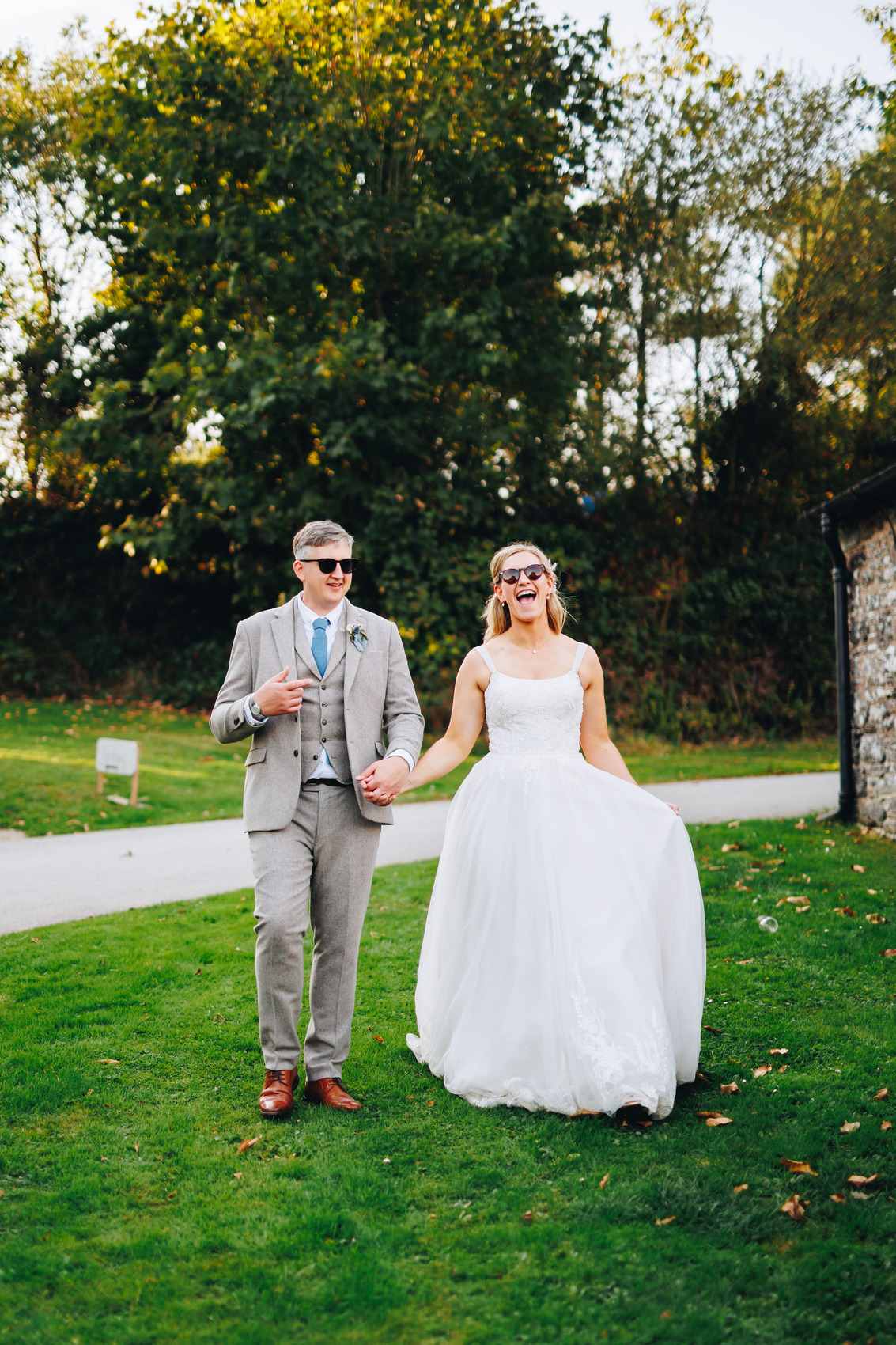 Bride and groom smiling while walking along the grass