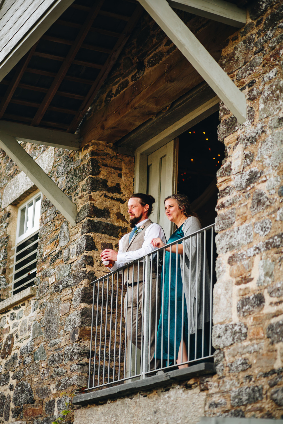 Two wedding guests standing at the balcony looking out