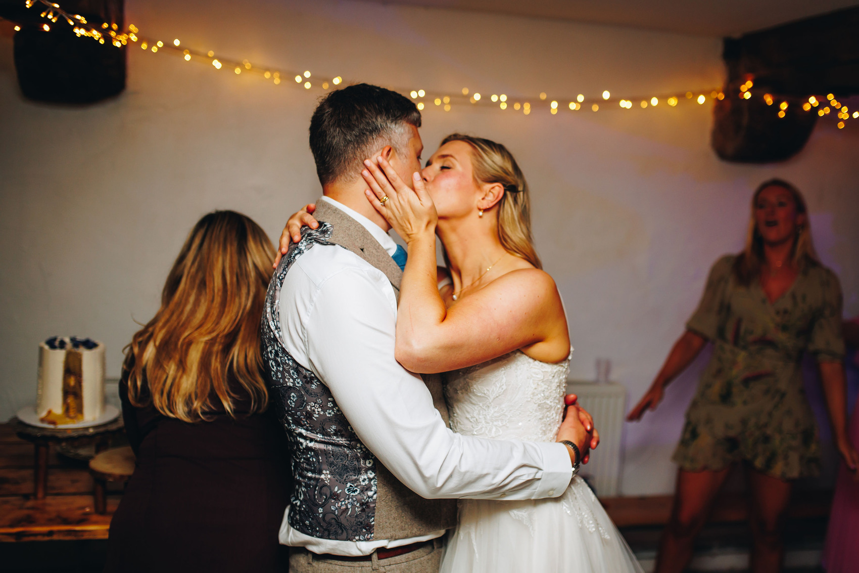 Bride and groom kissing with the freshly cut cake in the background